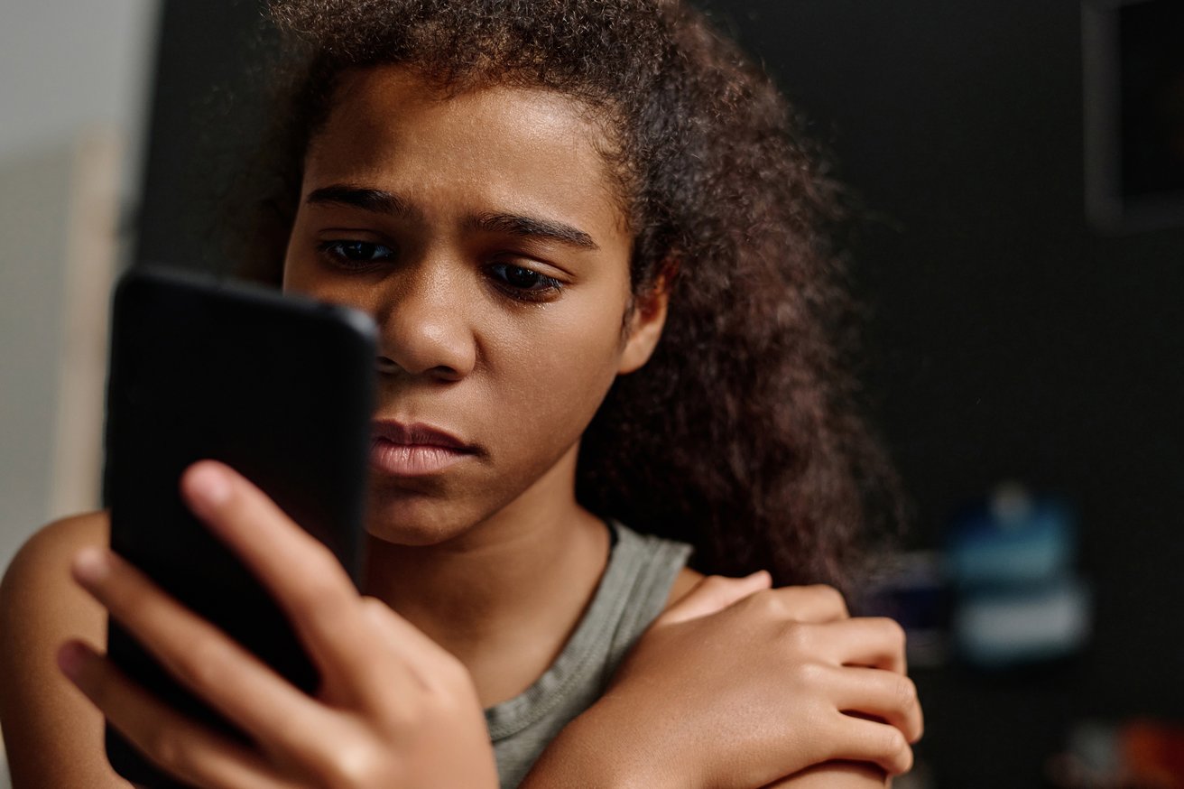 Teenage girl looks at her phone dejectedly like she's just been rejected