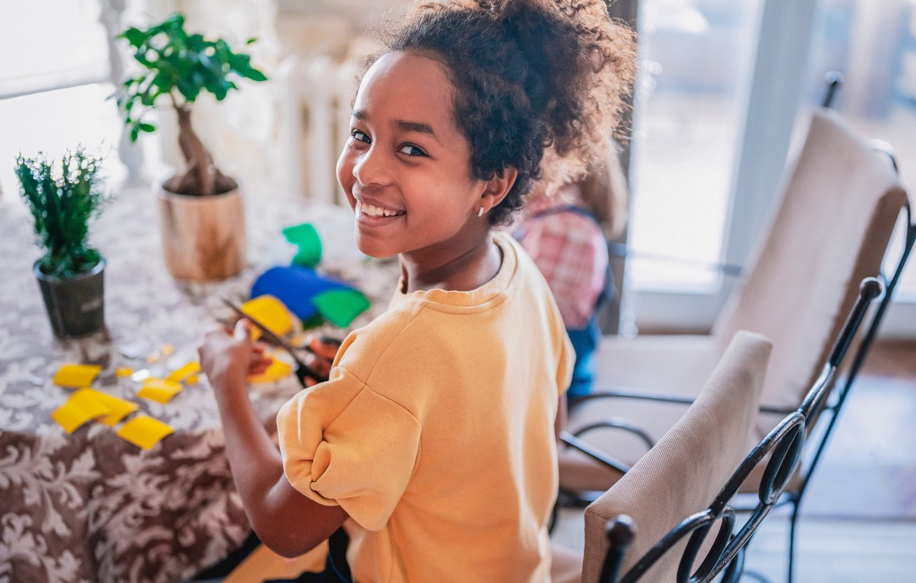 Little girl doing a craft at her kitchen table