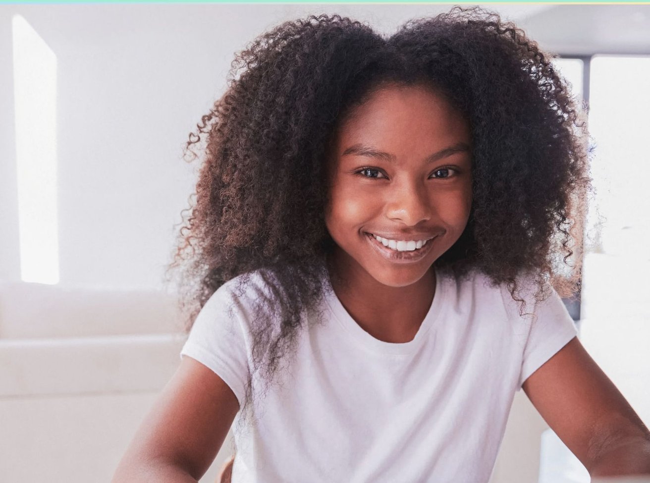 Young African American teen smiling at the camera in a white shirt