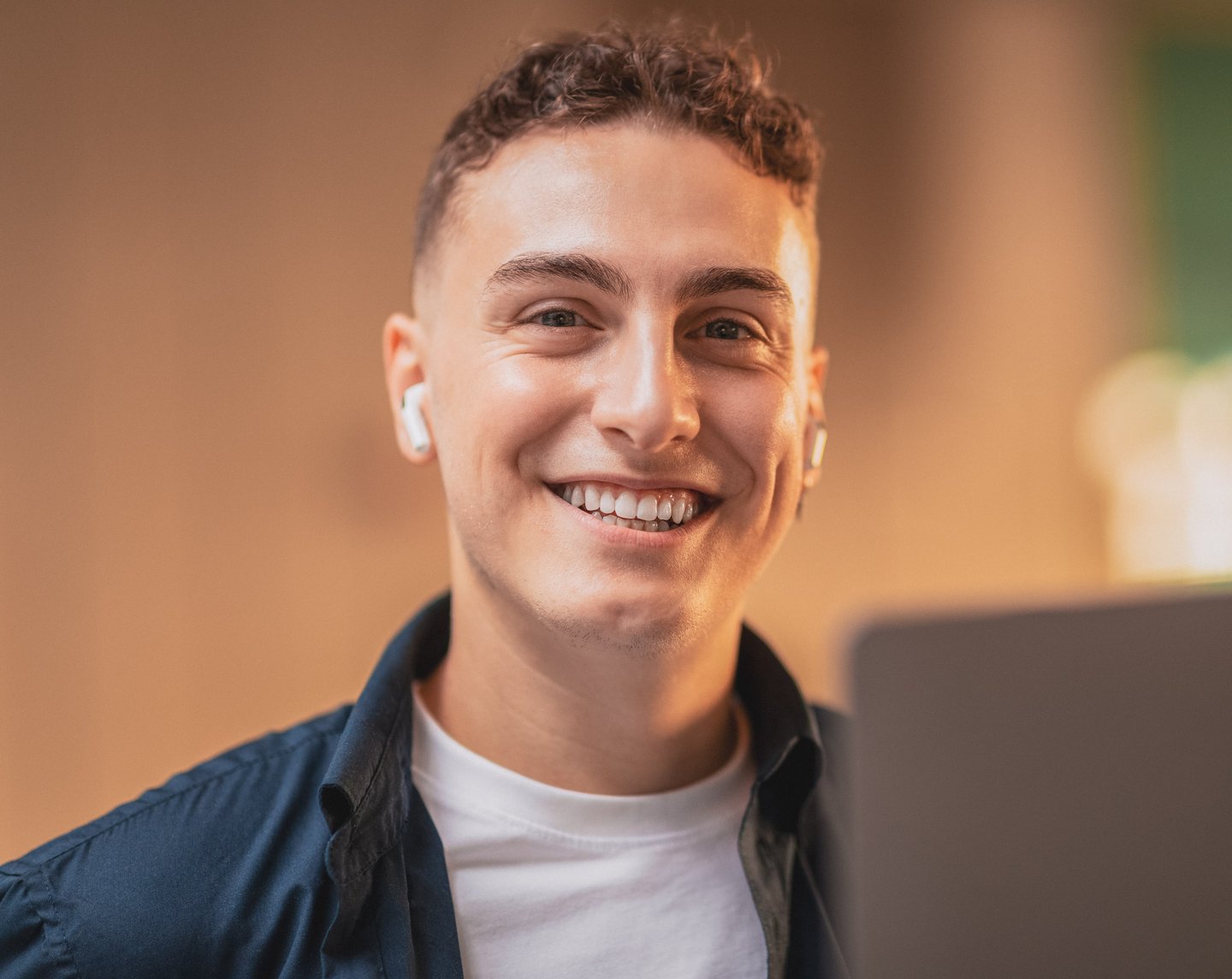 Young adult male smiling at the camera with earbuds in