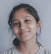 A young teenage girl with dark hair pulled back smiles gently at the camera. She appears calm and approachable in this headshot against a plain background.