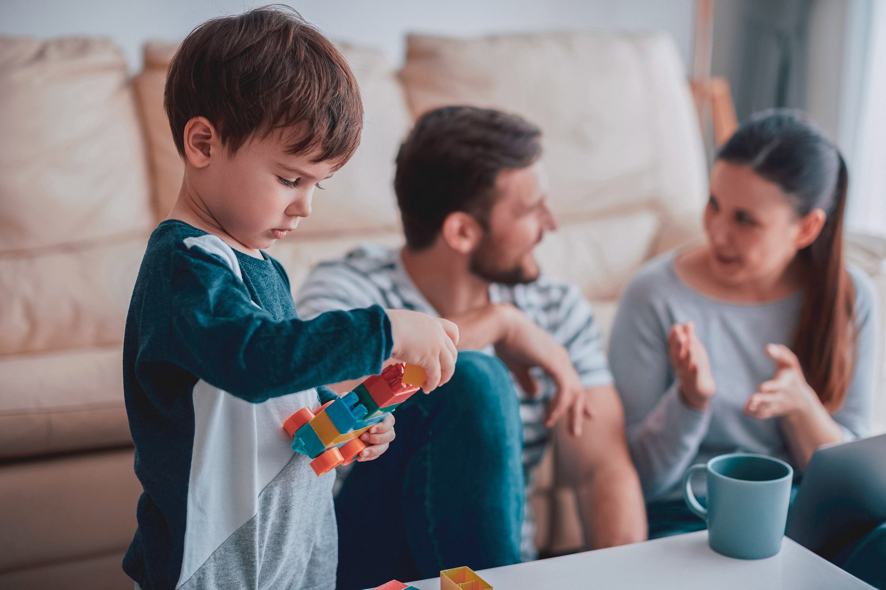 Child playing with toys while parents talk in the background
