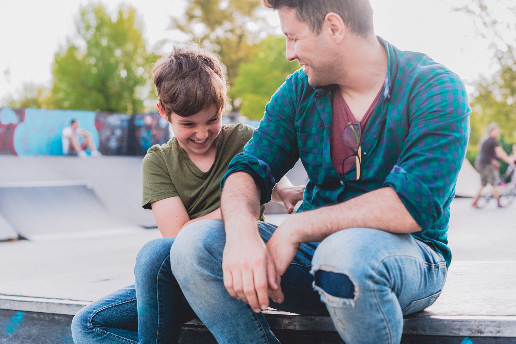 Dad and his son hanging out in a skatepark