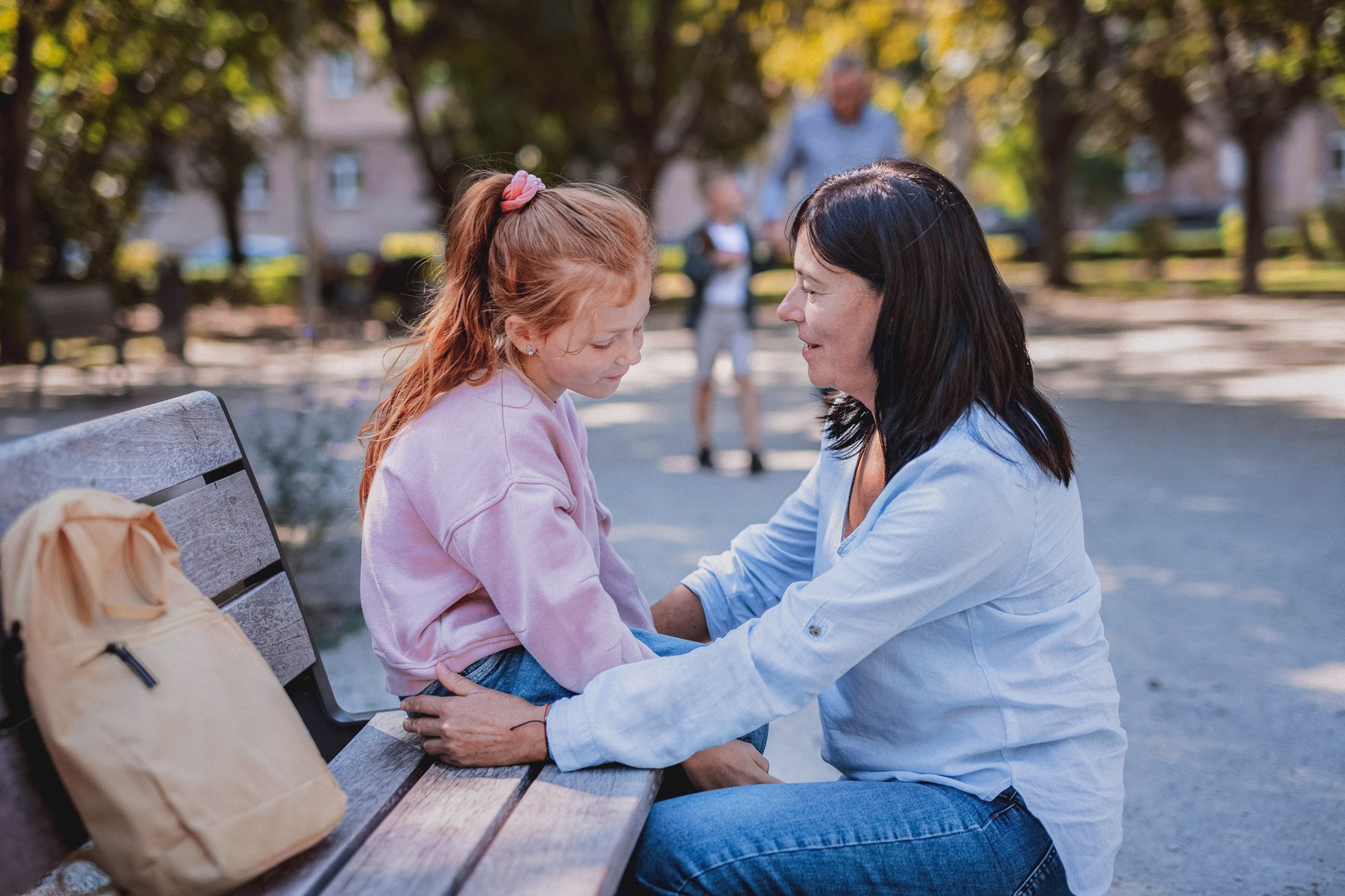 Kid dealing with anxiety while talking to her mom on a park bench
