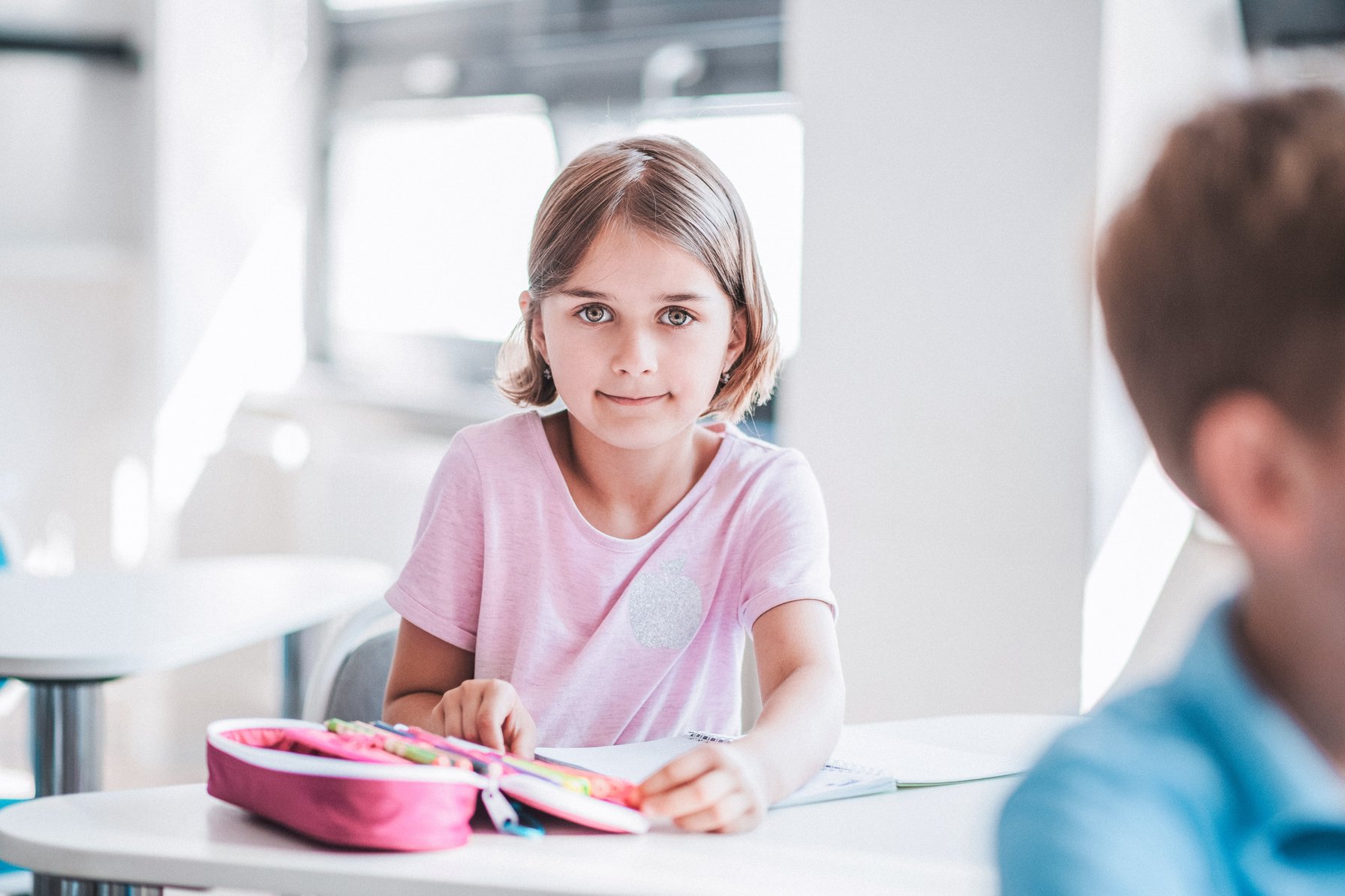Kid in school getting a pen out to take notes