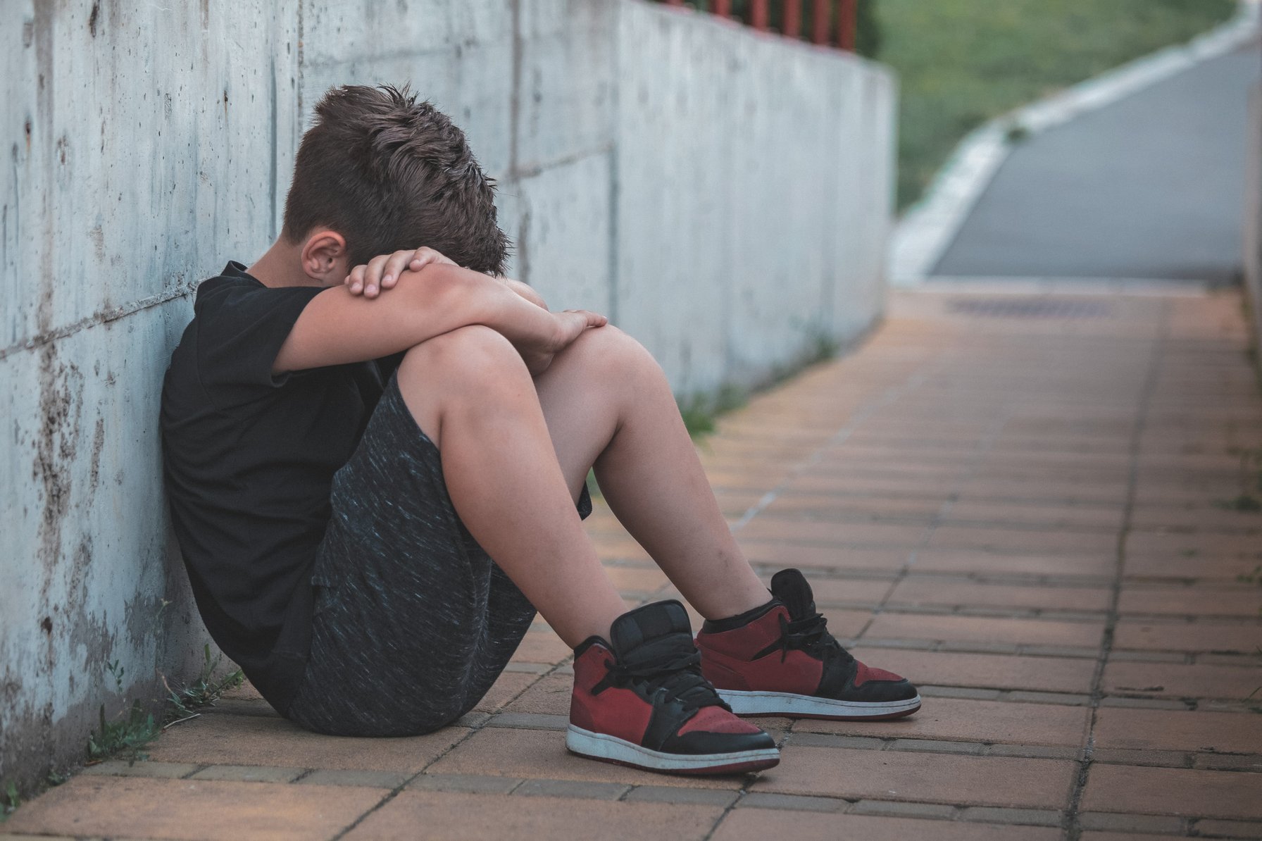 Kid sitting against wall crying from bullying