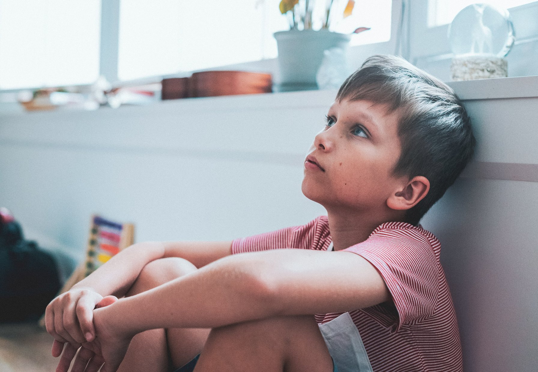 Kid with anxiety sitting on the ground looking up