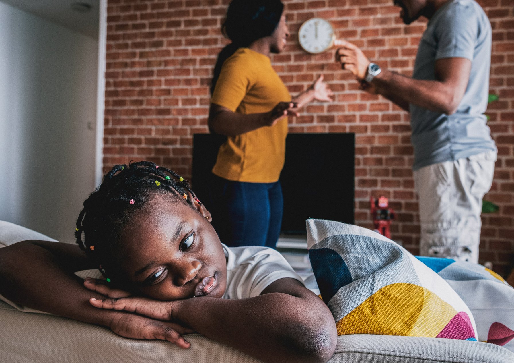 Parents arguing while daughter puts her head on a table